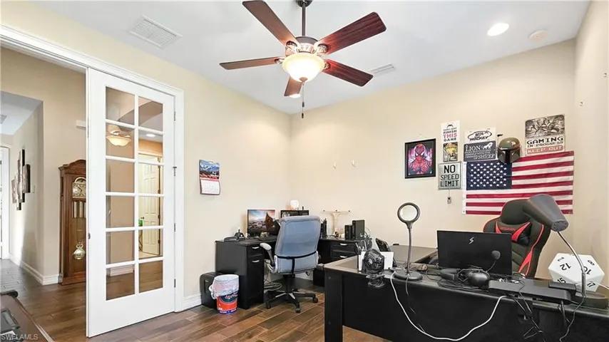 Office area with ceiling fan, dark hardwood / wood-style flooring, and french doors
