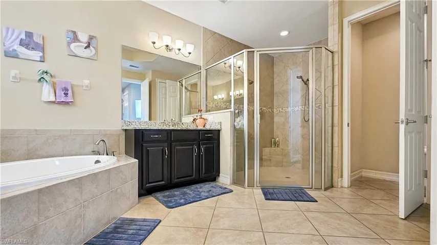 Bathroom featuring tile patterned flooring, vanity, and shower with separate bathtub