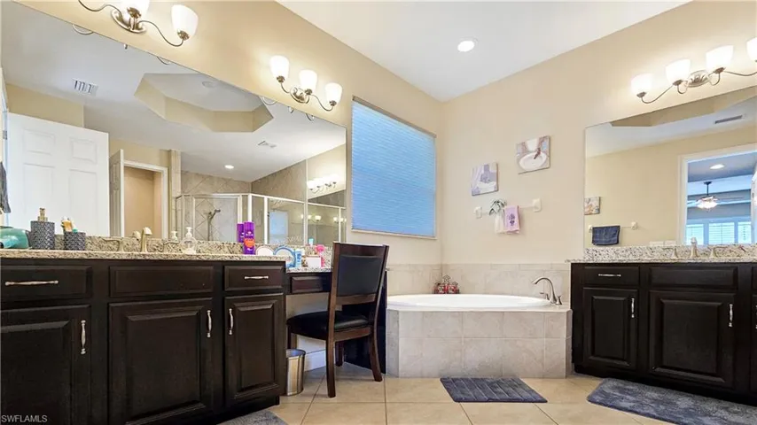 Bathroom featuring tile patterned flooring, shower with separate bathtub, and vanity