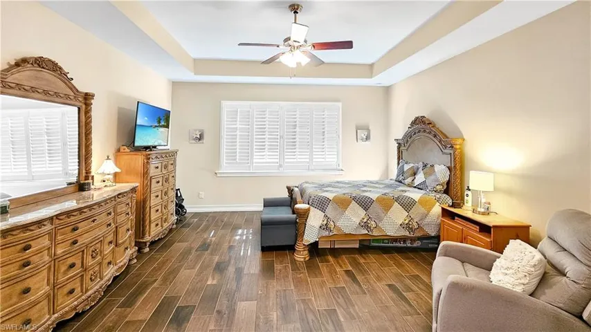 Bedroom featuring ceiling fan, dark hardwood / wood-style flooring, and a tray ceiling