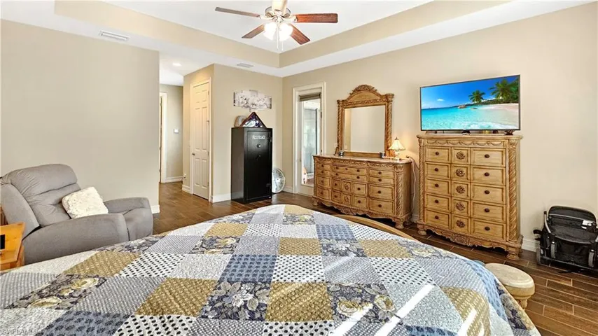 Bedroom with a tray ceiling, ceiling fan, a closet, and dark hardwood / wood-style floors