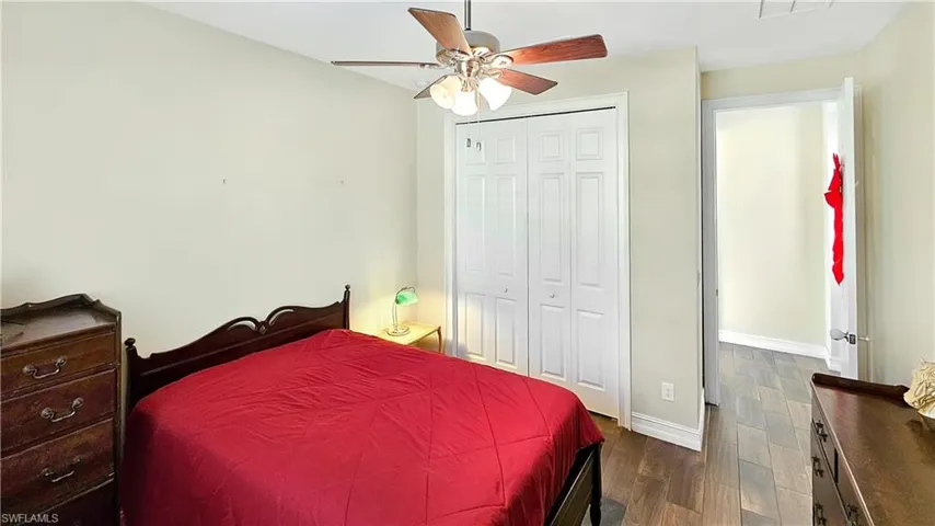 Bedroom with ceiling fan, dark hardwood / wood-style floors, and a closet