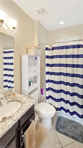 Full bathroom featuring tile patterned flooring, vanity, shower / bath combination with curtain, and toilet
