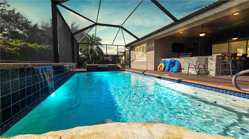 View of pool featuring pool water feature, a bar, and ceiling fan