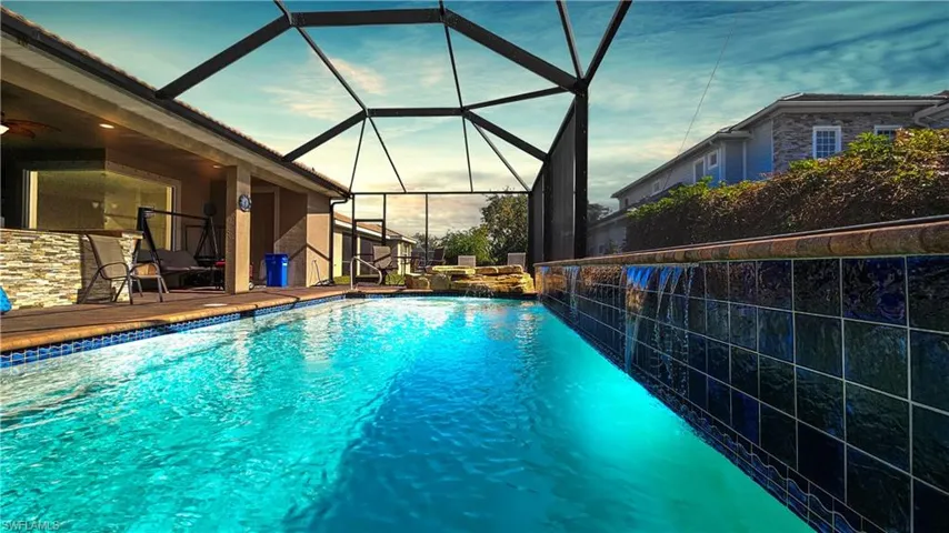 Pool at dusk with glass enclosure and a patio
