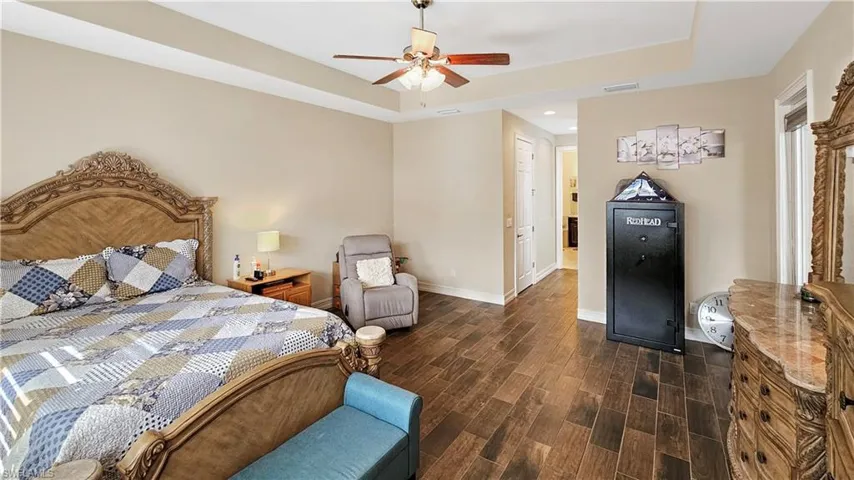 Bedroom with ceiling fan, a closet, dark hardwood / wood-style flooring, and a tray ceiling