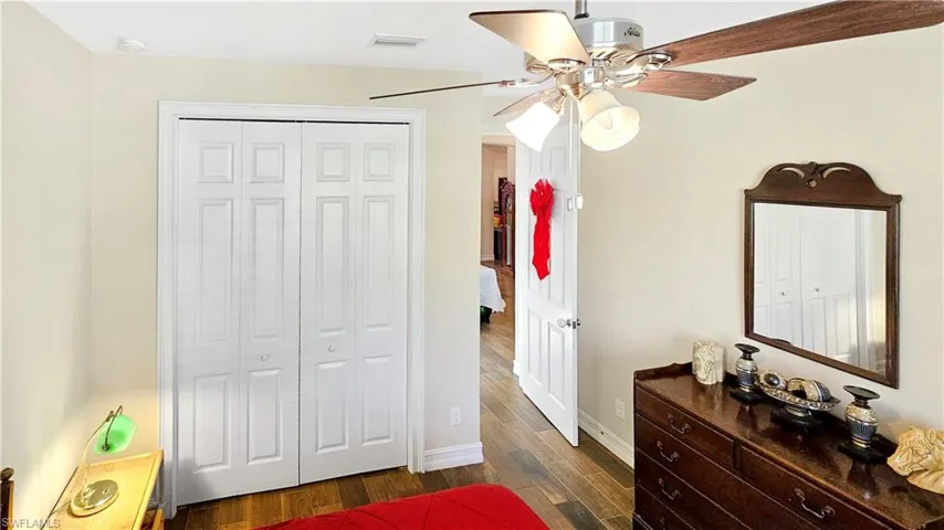Bedroom with ceiling fan, dark wood-type flooring, and a closet