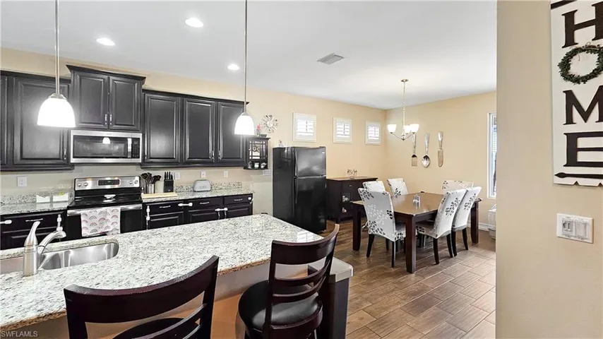Kitchen featuring dark wood-type flooring, pendant lighting, stainless steel appliances, and a kitchen breakfast bar