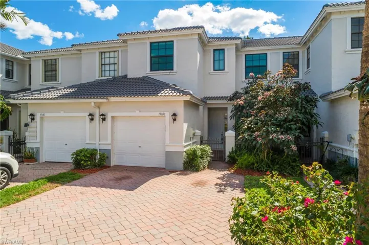 Mediterranean / spanish-style home featuring decorative driveway, a tiled roof, stucco siding, and a gate