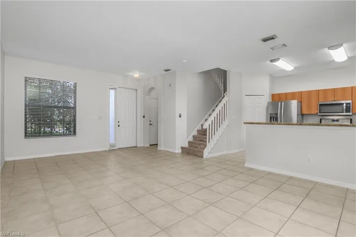 Unfurnished living room featuring stairs and arched walkways