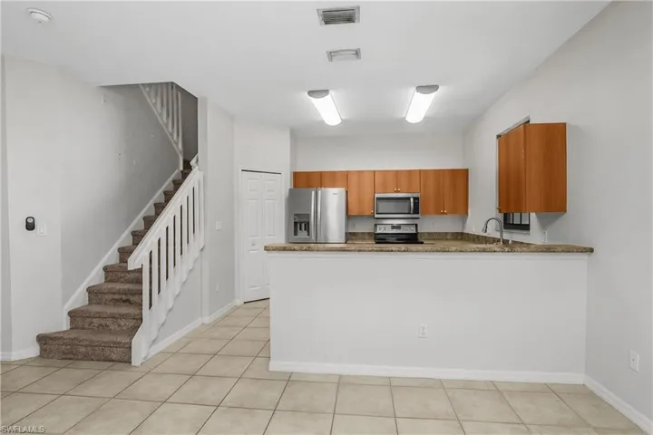 Kitchen featuring wood finish cabinetry, stainless steel appliances, dark stone counters, and a peninsula