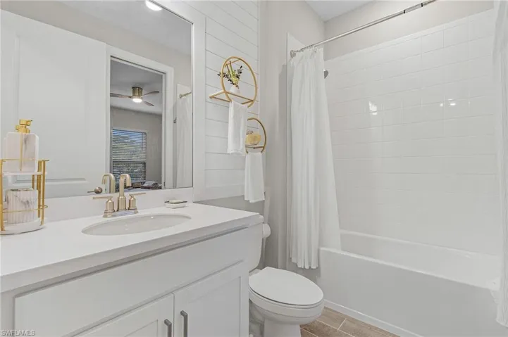 Full bathroom with ceiling fan, toilet, shower / tub combo with curtain, and vanity
