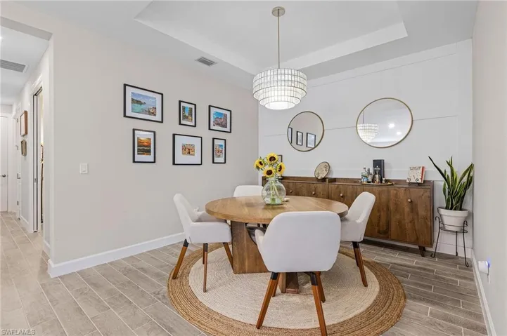 Dining area with a notable chandelier, a raised ceiling, and wood-type flooring