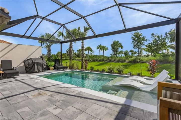 View of pool with glass enclosure, a grill, and a patio
