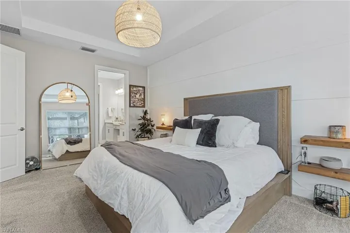 Bedroom with ensuite bath, carpet floors, and a tray ceiling