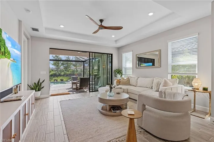 Living room featuring plenty of natural light, ceiling fan, and a raised ceiling