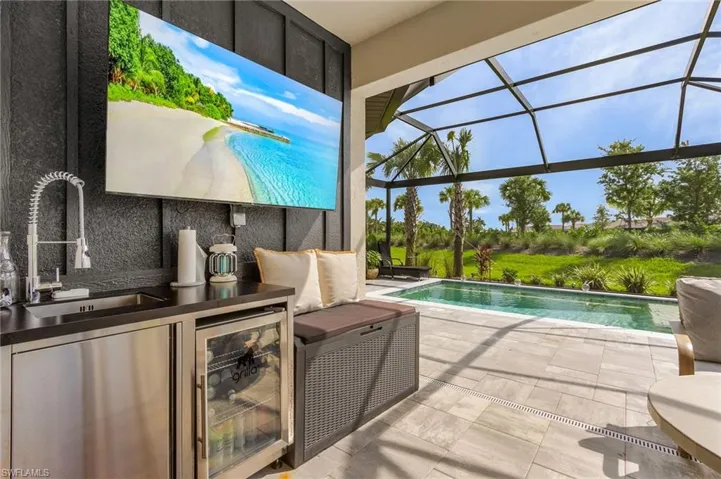 View of swimming pool featuring sink, glass enclosure, and a patio