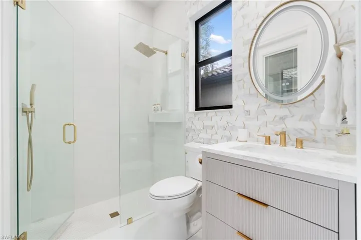 Bathroom with vanity, a stall shower, and tile walls