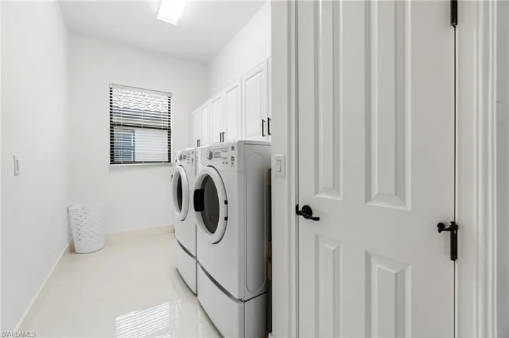 Washroom featuring separate washer and dryer and cabinet space