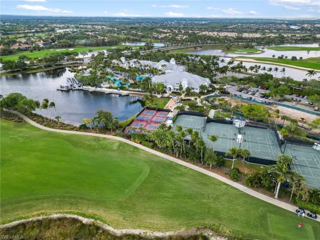 Aerial view of property and surrounding area featuring a large body of water, a golf course, and nearby suburban area