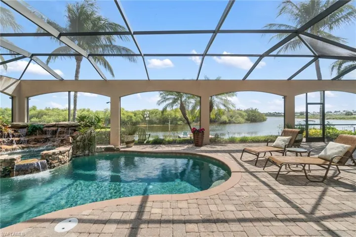 View of swimming pool with a patio area, glass enclosure, a water view, and a pool with connected hot tub
