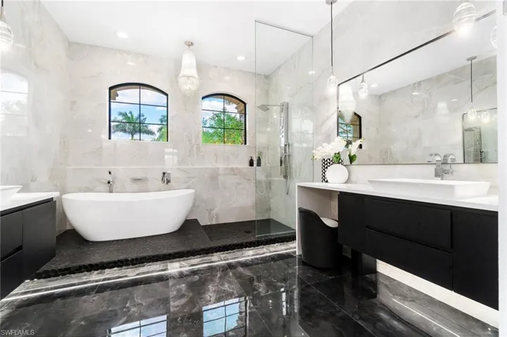 Bathroom featuring tile walls, marble tiled flooring, vanity, a soaking tub, and a tile shower
