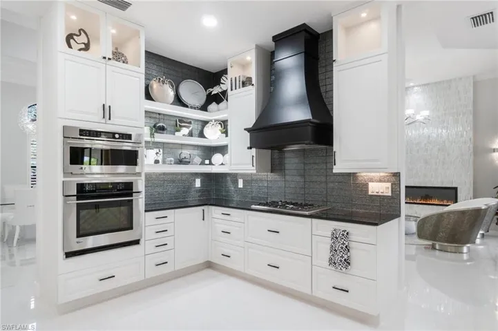 Kitchen featuring premium range hood, open shelves, backsplash, and stainless steel gas stovetop