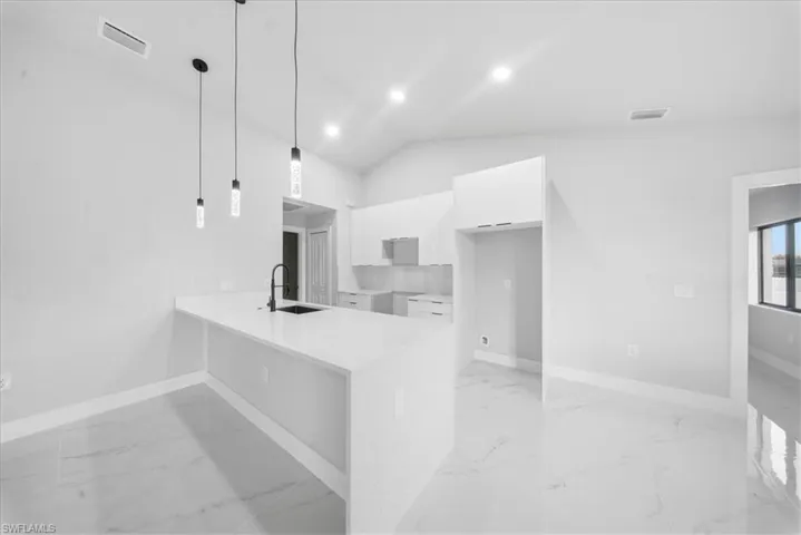 Kitchen with modern cabinets, light stone counters, a peninsula, white cabinets, and light marble finish flooring