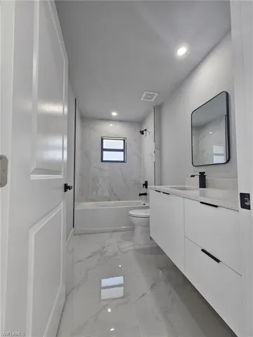 Full bathroom featuring vanity, tiled shower / bath combo, and toilet