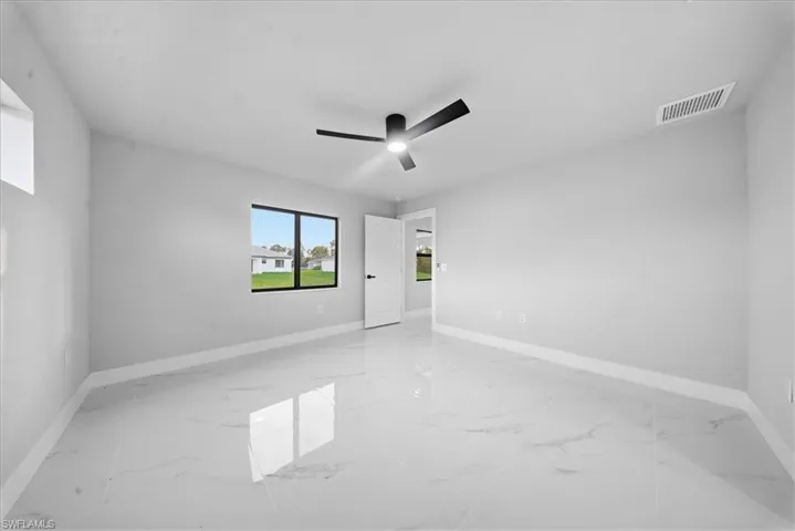 Spare room featuring light marble finish floors and a ceiling fan