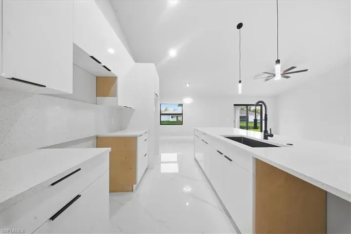 Kitchen with modern cabinets, white cabinetry, light stone counters, ceiling fan, and recessed lighting