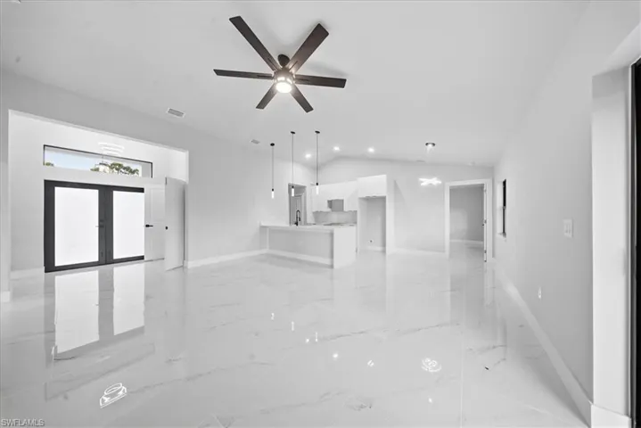 Unfurnished living room featuring light marble finish floors, lofted ceiling, ceiling fan, and recessed lighting