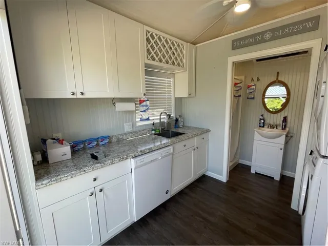 Kitchen with dishwasher, white cabinets, dark wood-type flooring, and sink