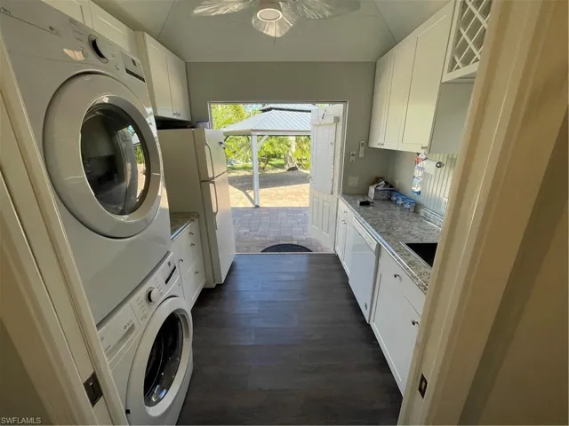 Laundry room featuring dark hardwood / wood-style floors, ceiling fan, cabinets, and stacked washer and dryer