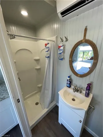 Bathroom with a shower with curtain, vanity, hardwood / wood-style flooring, and an AC wall unit