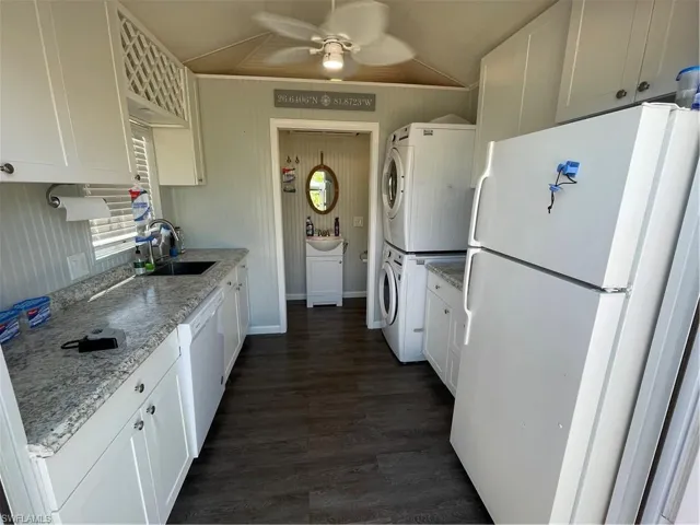 Kitchen with white cabinetry, dishwasher, dark hardwood / wood-style floors, refrigerator, and stacked washer / drying machine