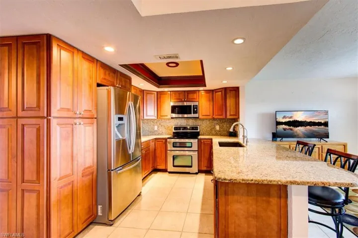Kitchen with sink, kitchen peninsula, tasteful backsplash, appliances with stainless steel finishes, and a kitchen breakfast bar