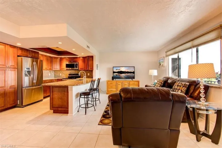 Tiled living room with a textured ceiling, a tray ceiling, and sink