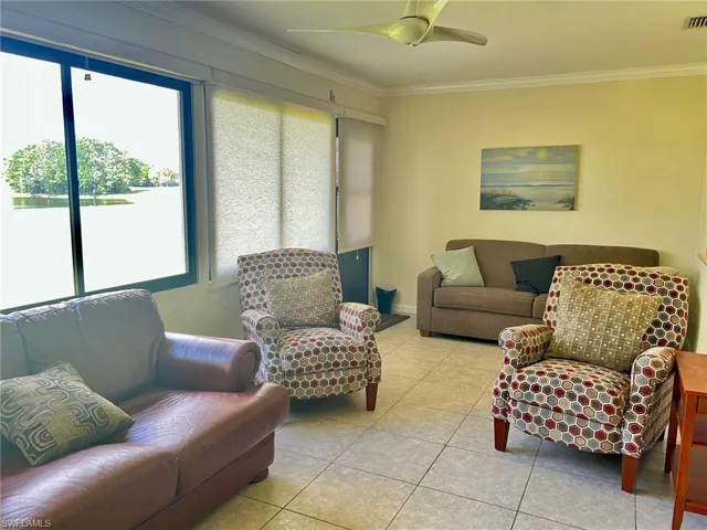 Living area featuring crown molding, tile patterned floors, and ceiling fan
