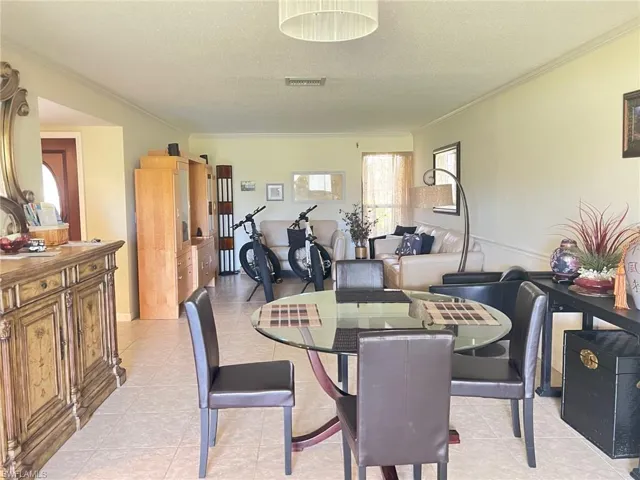 Dining area featuring ornamental molding, a textured ceiling, and light tile patterned floors