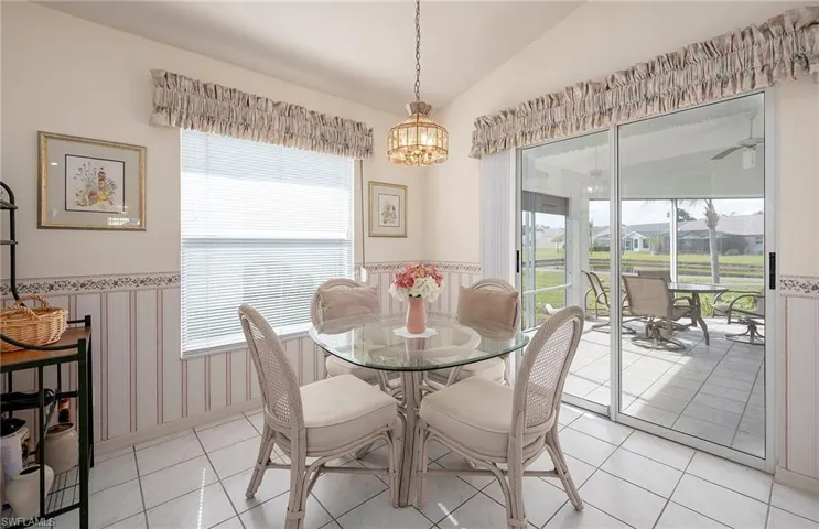 Tiled dining space featuring vaulted ceiling