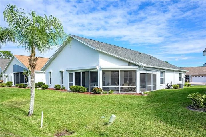 Back of house with a lawn, and a sunroom