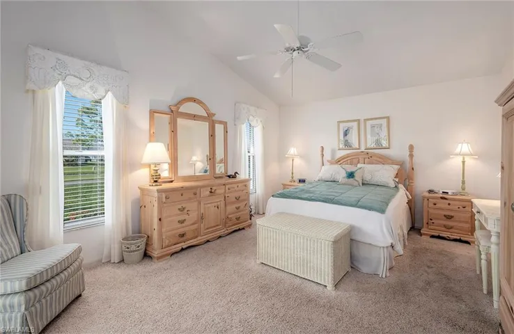Primary Bedroom with light colored carpet, high vaulted ceiling, and ceiling fan