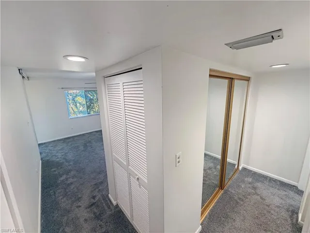 Corridor with dark colored carpet and baseboards