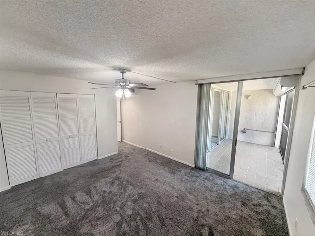 Unfurnished bedroom featuring a closet, carpet floors, a textured ceiling, a ceiling fan, and access to outside