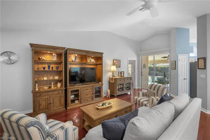 Living room with vaulted ceiling, dark hardwood / wood-style floors, and ceiling fan