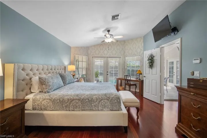 Bedroom with lofted ceiling, ceiling fan, access to exterior, dark hardwood / wood-style floors, and french doors