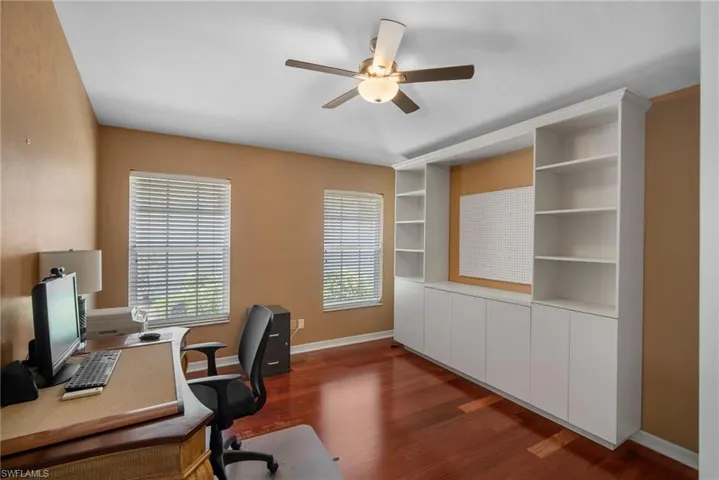 Unfurnished office with ceiling fan and dark hardwood / wood-style flooring