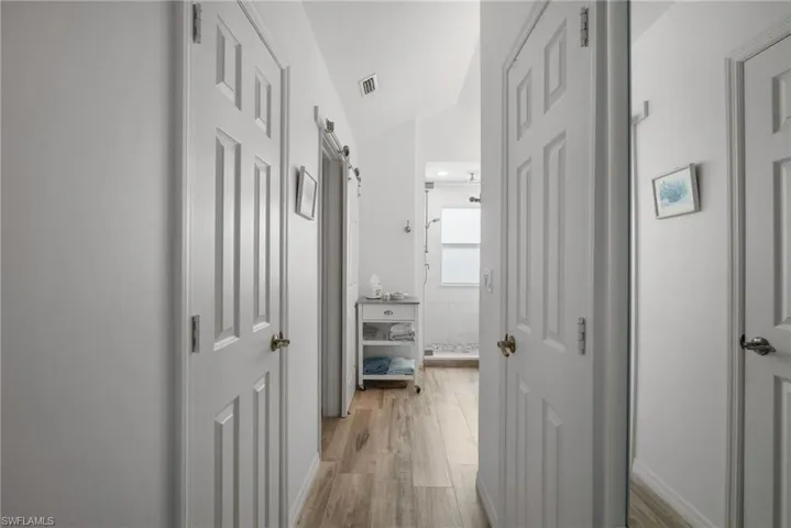 Hall with vaulted ceiling, a barn door, and hardwood / wood-style flooring