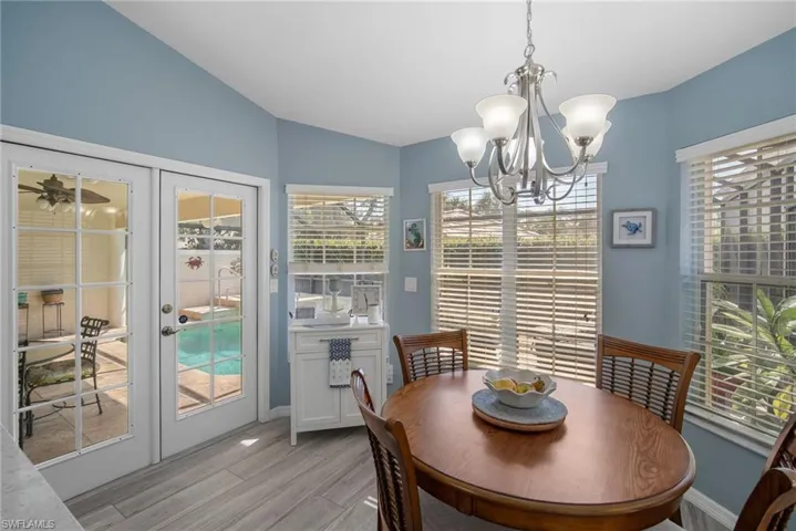 Dining room with french doors, a notable chandelier, lofted ceiling, and light hardwood / wood-style flooring